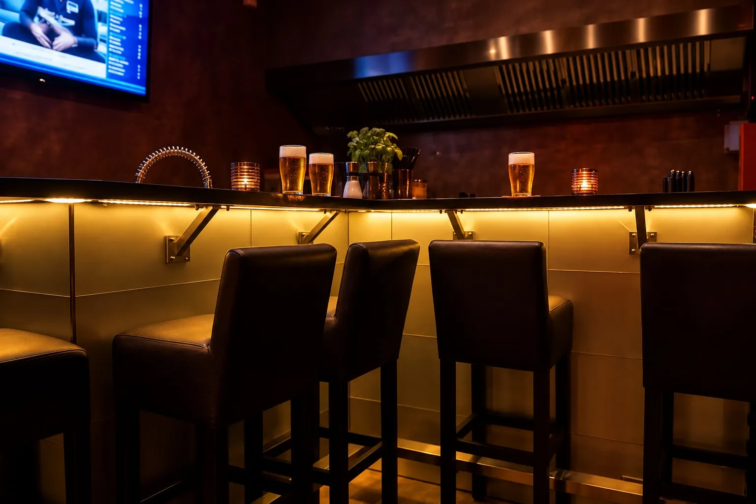 Bar mit Barhockern, beleuchtetem Tresen und frisch gezapftem Bier